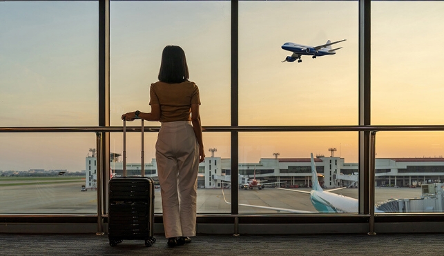 Woman looking out the window to a plane taking off